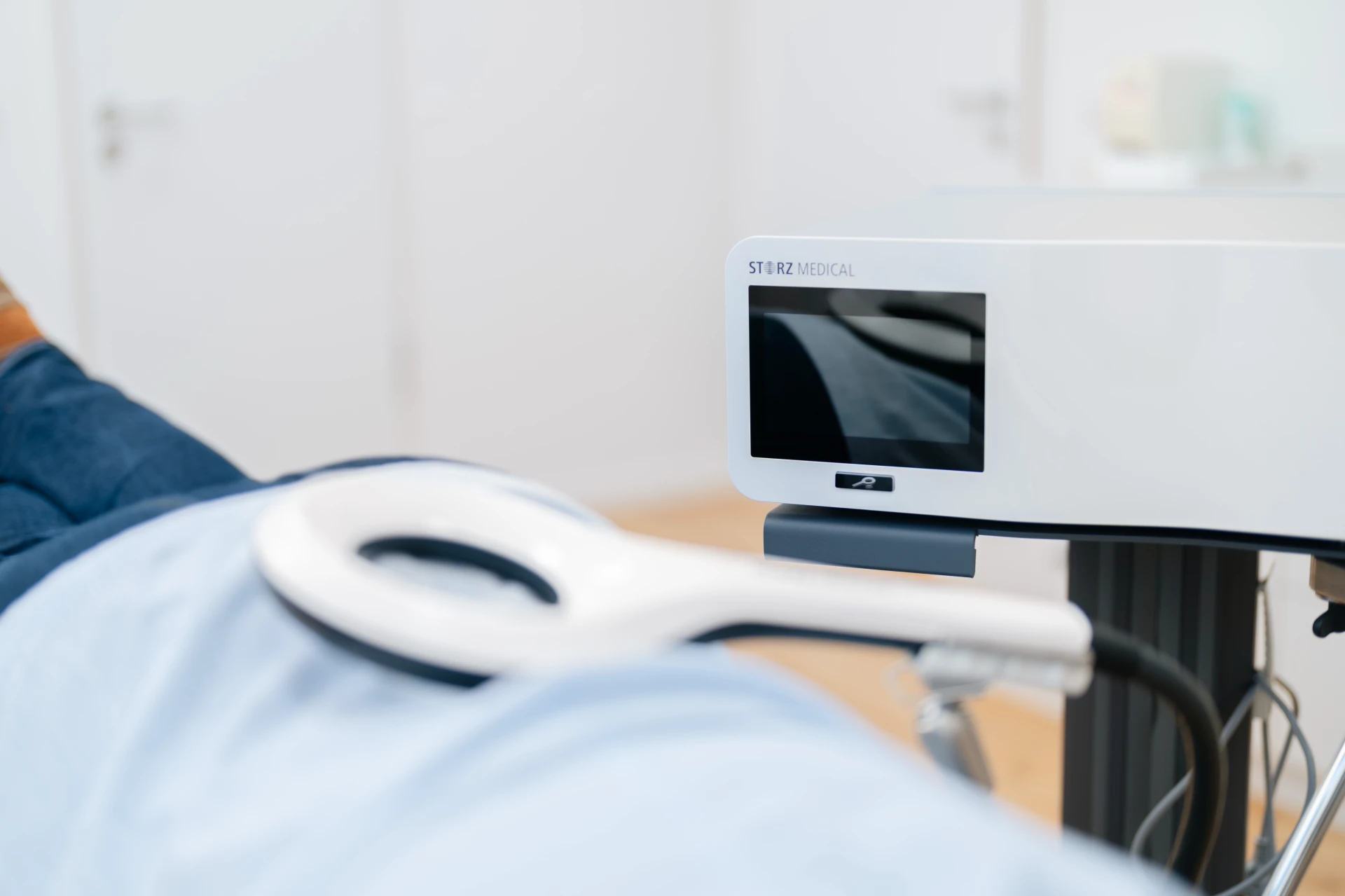 EMTT — Magnetotransduktionstherapie Frau liegt entspannt auf einer Liege, während ein medizinisches Gerät auf ihren Rücken gerichtet ist.