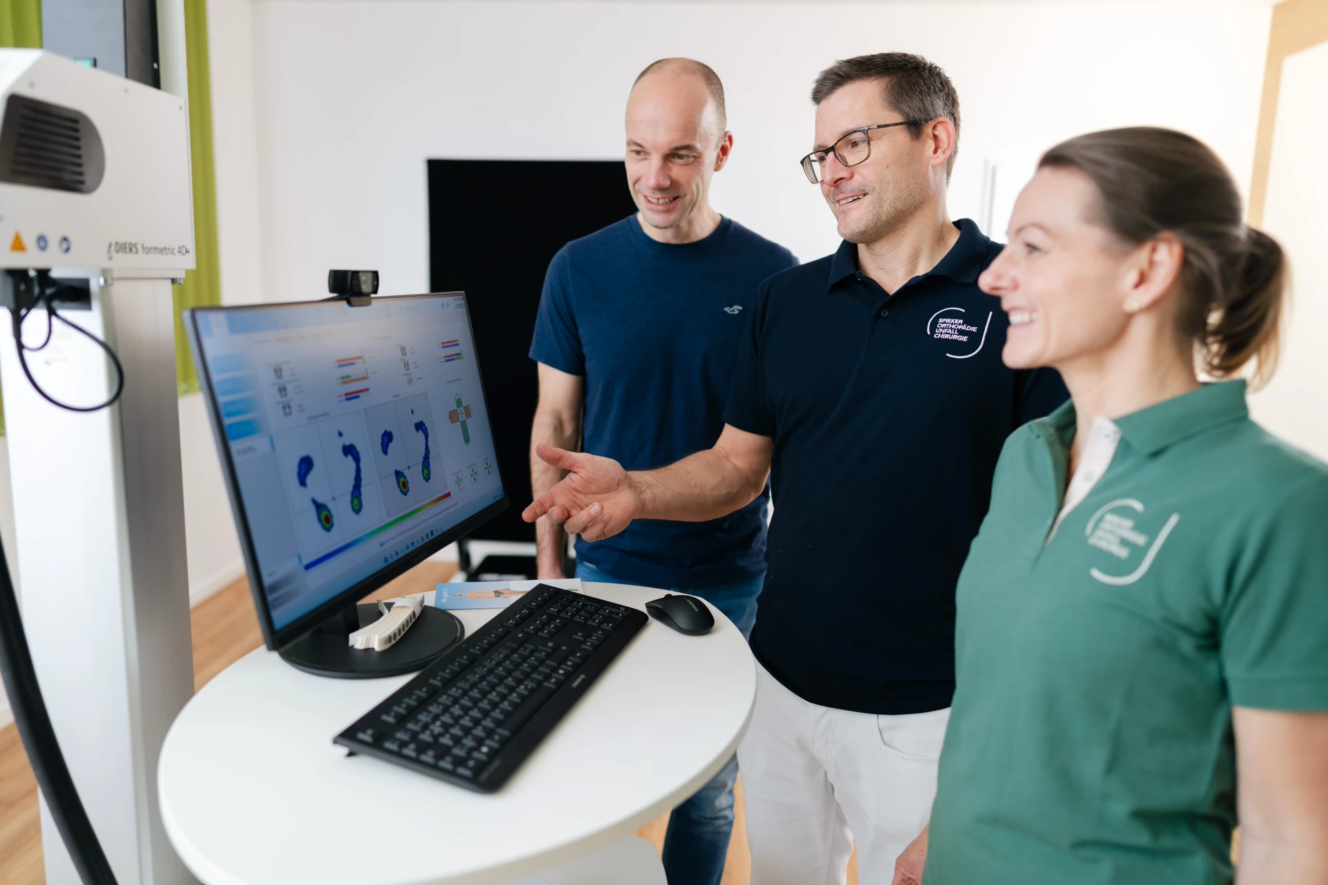 Drei Personen betrachten gemeinsam Daten auf einem Computerbildschirm in einem modernen, hellen Raum.