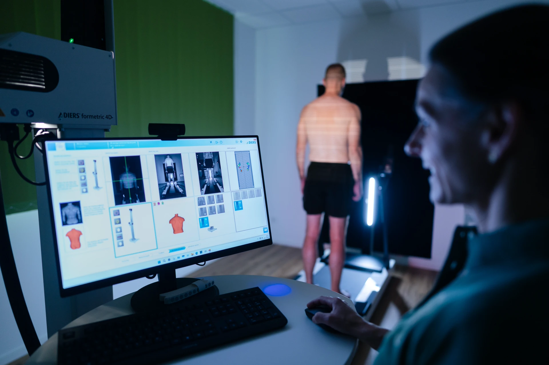 Plantarfasziitis behandeln in Rietberg Eine Person steht vor einem Bildschirm, während Daten zur Körpervermessung analysiert werden.