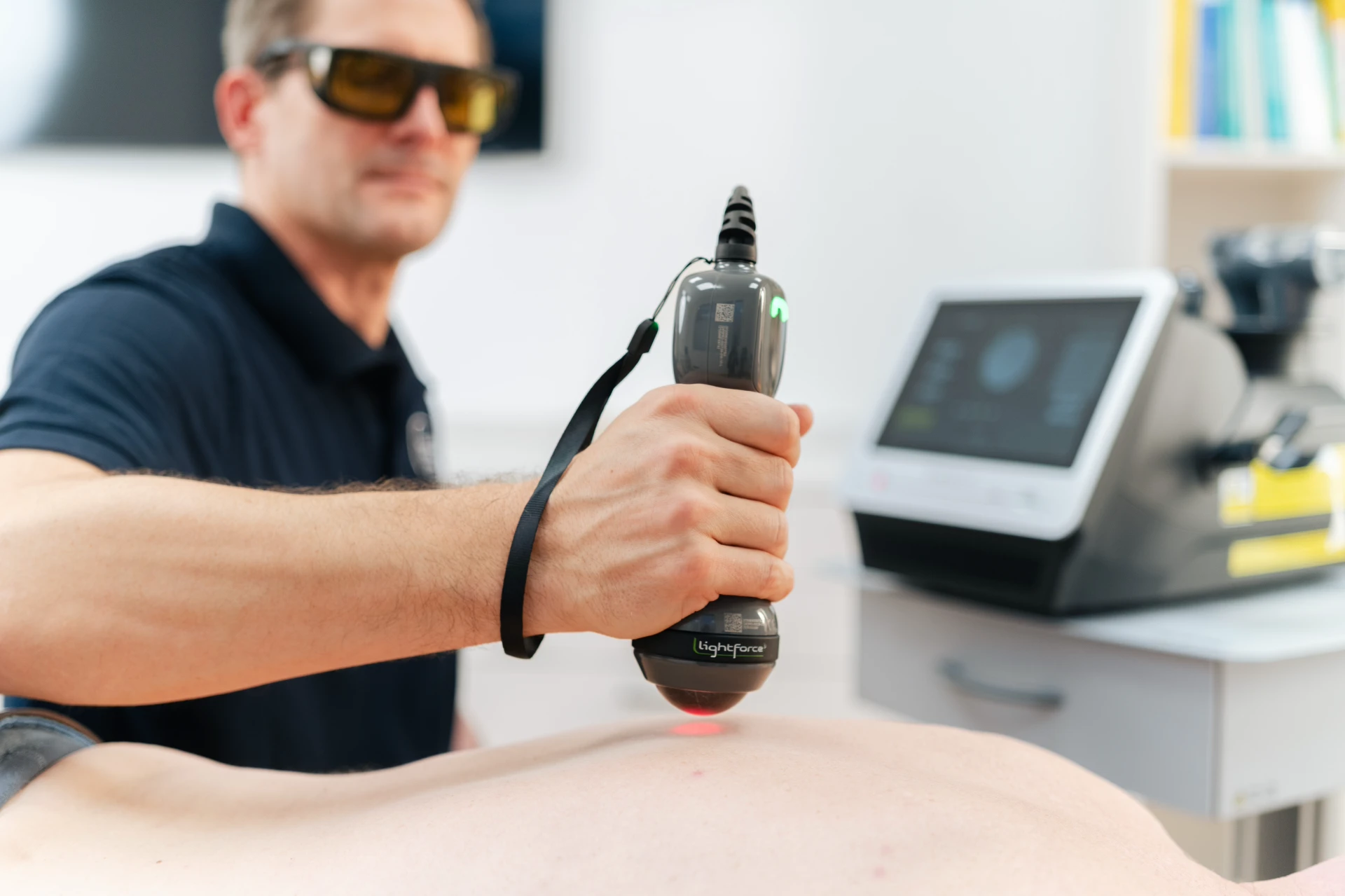 Hochenergie-Tiefenlaser Ein Behandler nutzt ein Lasergerät zur Therapie auf dem Rücken eines Patienten.